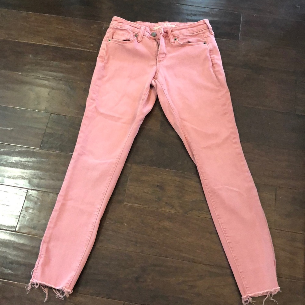 Pink jeans with frayed bottoms.